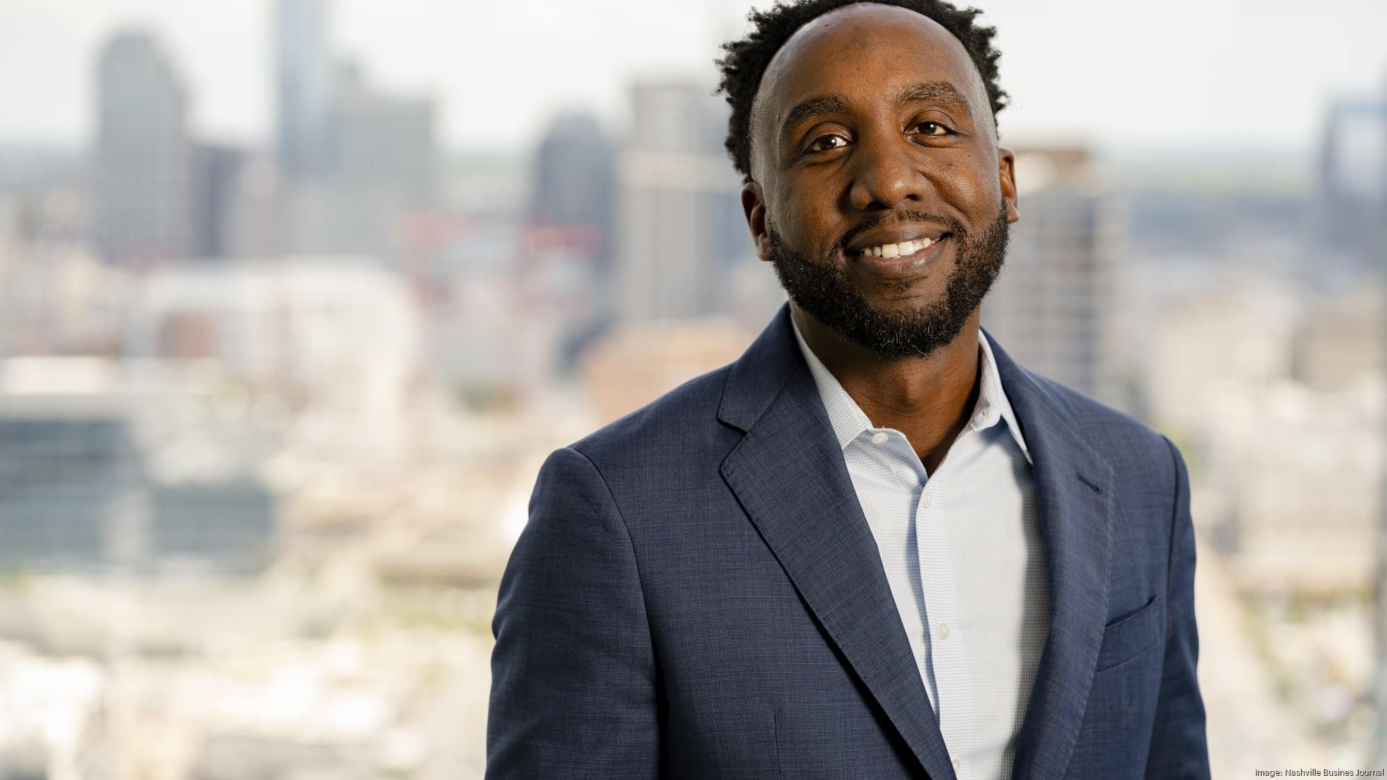 A Man Wearing A Suit And Tie Smiling At The Camera