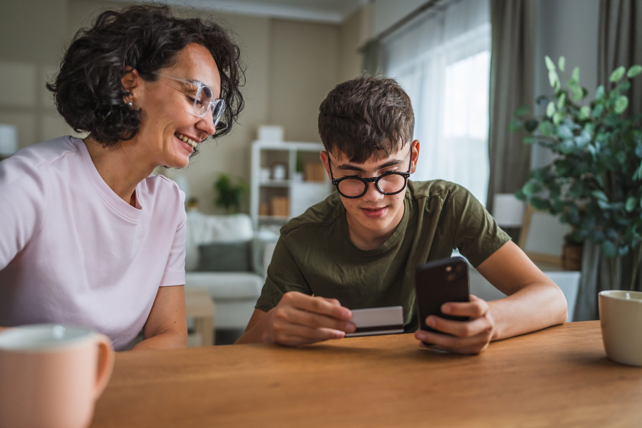 A mom and teen son reviewing mobile banking together, illustrating financial literacy for teenagers in Nashville, TN.
